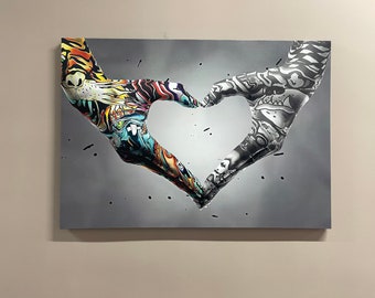 May include: Two hands with colorful and black and white graffiti designs form a heart shape against a gray background.