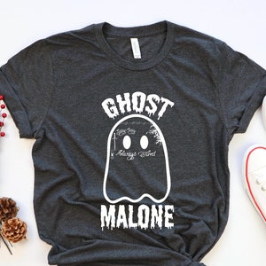 May include: A dark gray t-shirt with a white ghost graphic and the text "Ghost Malone" in white. The ghost has the words "Stay Spooky" and "Always Tired" written inside it.