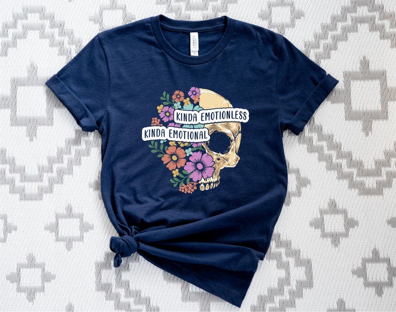 Puede incluir: Una camiseta azul marino con un gr&aacute;fico de calavera. La calavera est&aacute; medio cubierta de flores y tiene el texto "Kinda Emotional" y "Kinda Emotionless" en ella.