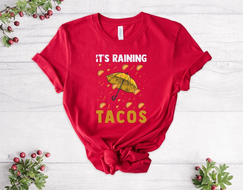 Peut inclure: T-shirt rouge avec un parapluie jaune et le texte "Il pleut des tacos".