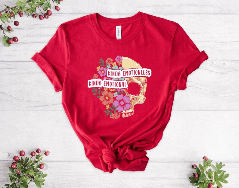 Puede incluir: Camiseta roja con un gr&aacute;fico de calavera y dise&ntilde;o floral. El texto "Kinda Emotional" y "Kinda Emotionless" est&aacute; impreso en la camiseta.