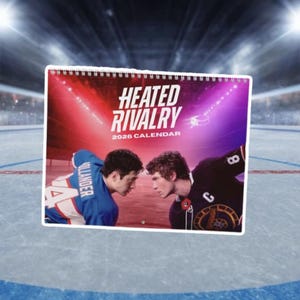 May include: A 2026 calendar titled "Heated Rivalry" featuring two hockey players facing each other. The calendar has a red, purple, and white color scheme. One player wears a blue jersey, and the other wears a black jersey.