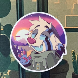 May include: A sticker featuring a cartoon animal with white fur, blue eyes, and a black and blue striped pattern on its face. The animal is wearing a green jacket and is waving with its right paw. The background is a purple and pink sunset with a white moon.