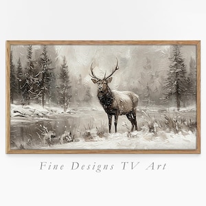 May include: A framed landscape painting depicts a majestic elk in a snowy forest scene. The artwork, in shades of gray and brown, features a river and evergreen trees. The text "Fine Designs TV Art" is at the bottom.