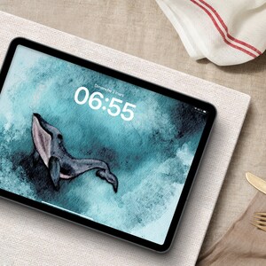 May include: A tablet computer displaying a digital clock with the time 06:55 and the date "Dimanche 3 mars". The background image is a watercolor painting of a whale swimming in the ocean.