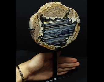 Peut inclure: Une géode d'agate ronde avec un intérieur à bandes noires et blanches. La géode est montée sur un support en métal noir.