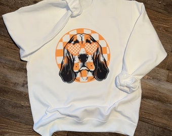 May include: White sweatshirt with a black and white illustration of a dog wearing heart-shaped sunglasses. The dog is surrounded by a checkered orange and white circle.