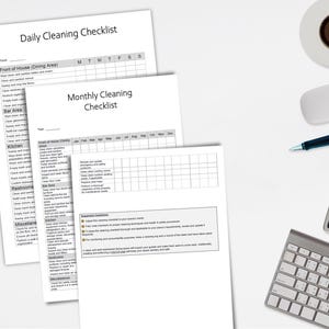 Könnte beinhalten: Draufsicht auf einen Arbeitsplatz mit Reinigungs-Checklisten, einer Kaffeetasse, einer Computermaus, einem Stift, einem Taschenrechner und einer Tastatur. Die Checklisten tragen die Titel "Daily Cleaning Checklist" und "Monthly Cleaning Checklist".