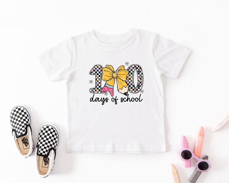 A white t-shirt with a graphic design, a pair of black and white checkered shoes, and some children's school supplies like pencils and sunglasses are arranged on a white background.