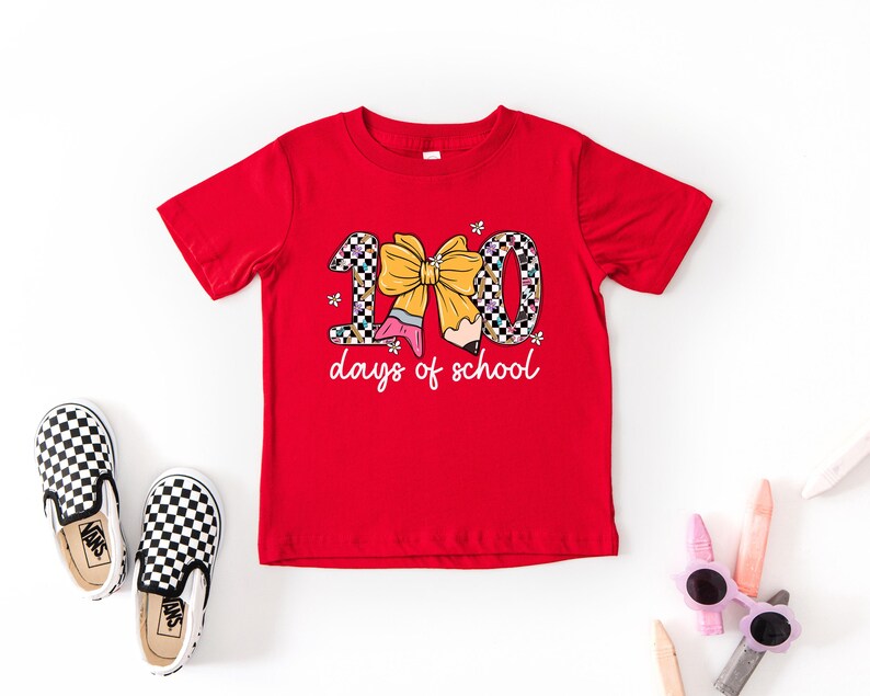 A red t-shirt with a graphic design, a pair of black and white checkered shoes, and some children's sunglasses on a white background.