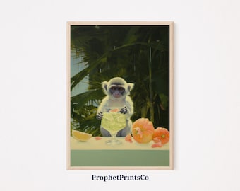 May include: A framed print featuring a monkey holding a cocktail in a stemmed glass. The monkey is light gray with a dark face, set against a backdrop of lush green foliage. A lemon slice and orange fruit are on the table. The text "ProphetPrintsCo" is at the bottom.