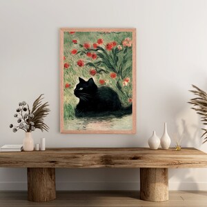 K&ouml;nnte beinhalten: Ein gerahmter Druck eines schwarzen Katers, der in einem Feld mit roten Blumen sitzt. Die Katze hat blaue Augen und schaut nach links. Die Blumen bl&uuml;hen und der Hintergrund ist ein gr&uuml;nes Feld.