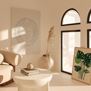 May include: A white couch with a beige cushion sits in a room with a large window, a framed print of tropical leaves, and a canvas print of a Buddha face.