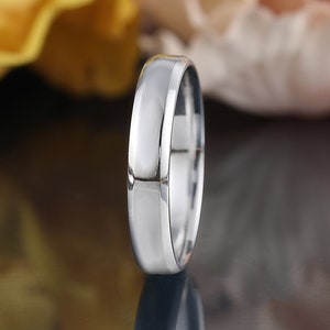 May include: A simple silver wedding band with a slightly rounded edge and a brushed finish.
