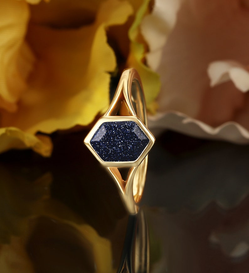 May include: A gold ring with a hexagonal blue stone set in the center. The stone has a sparkly, textured surface.