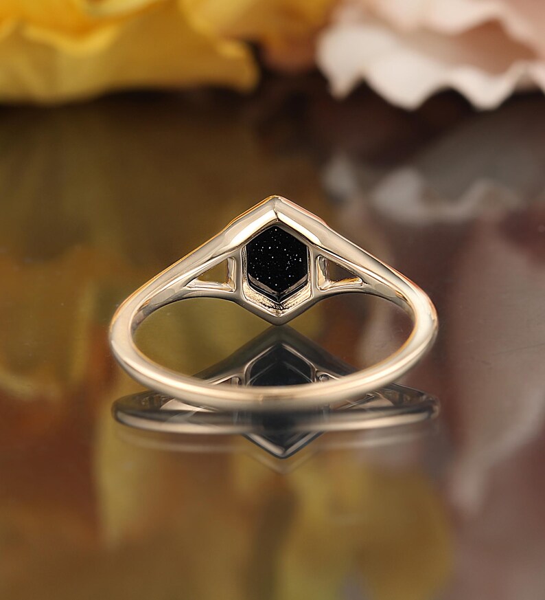 May include: A gold ring with a black hexagonal stone set in a geometric design.