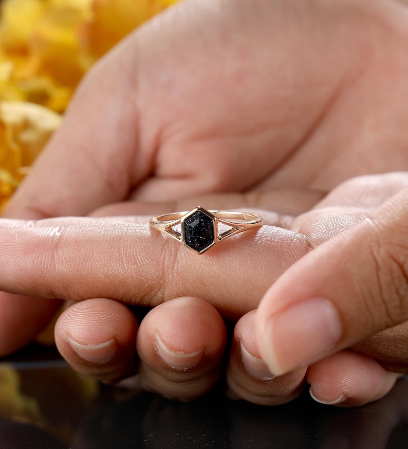 May include: A gold ring with a black hexagonal stone set in a geometric design.