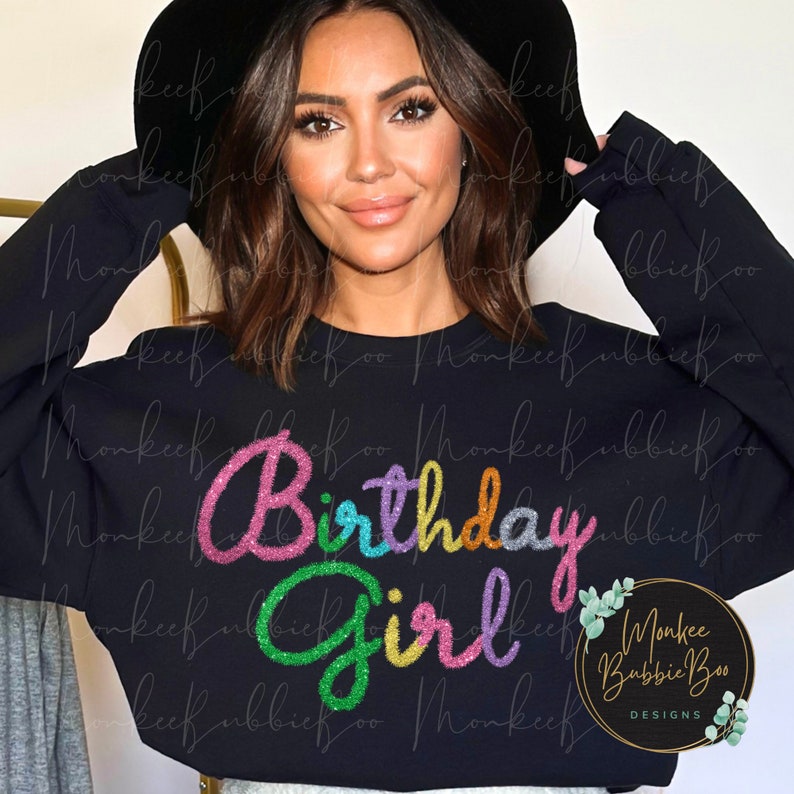 May include: A black sweatshirt with the text "Birthday Girl" in rainbow glitter lettering.