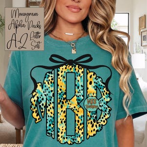 May include: Teal t-shirt featuring a monogram design with the letters "MBB" in a leopard print pattern with black accents. The shirt also has the text "Monogram Alpha Packs A-Z Letter Sets" and "MBB Designs".