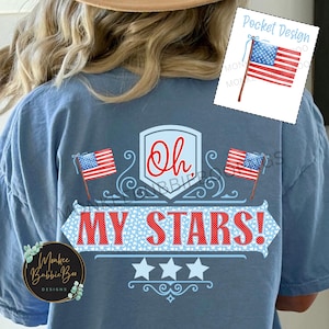 May include: A blue t-shirt with a red, white, and blue patriotic design. The design features two American flags, a banner that says "Oh My Stars!" and three stars. The shirt is perfect for celebrating Independence Day or showing your American pride.