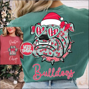 May include: Green t-shirt featuring a bulldog design with a Santa hat and heart-shaped sunglasses. The bulldog is decorated with a floral pattern. The word "Bulldogs" is written in a cursive font. A smaller image shows a red sweatshirt with a paw print design.