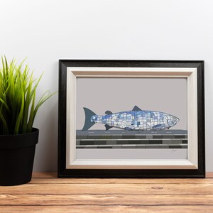 May include: A framed print of a blue and white mosaic salmon sculpture. The salmon is on a grey background with a black frame.