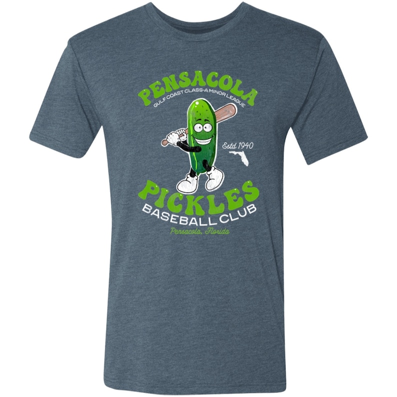May include: A blue t-shirt featuring a vintage-style graphic of a cartoon pickle holding a baseball bat. The graphic reads "Pensacola Gulf Coast Class-A Minor League Pickles Baseball Club Pensacola, Florida Est. 1940".