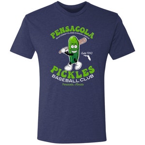 May include: A navy blue t-shirt featuring a cartoon pickle holding a baseball bat. The text on the shirt reads "Pensacola Gulf Coast Class-A Minor League Pickles Baseball Club Pensacola, Florida Estd 1940".