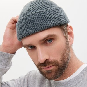 May include: A gray knitted beanie with a folded brim. The beanie is made of a soft, comfortable material and has a relaxed fit.