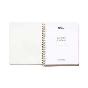 Opening title page of the Quarterly Plans 90-Day Planner with gold spiral binding, white interior pages, and minimalist Friday Afternoons branding.