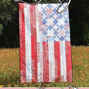May include: A patriotic quilt with a design resembling the American flag. The quilt features red and white stripes, a blue square with white stars, and the word "Liberty" in cursive. The quilt is displayed outdoors.