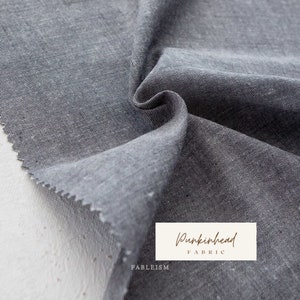 May include: Close-up of a dark gray textured fabric with a subtle pattern. The fabric is folded and draped, showcasing its soft texture. The text "Pumpkinhead Fabric" is visible in the lower right corner.
