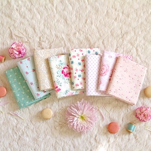 Puede incluir: Vista a&eacute;rea de varias telas con estampados florales y de lunares en colores pastel. Las telas est&aacute;n dispuestas con macarons, flores y carretes de hilo sobre una superficie blanca texturizada. Una colecci&oacute;n de suministros de artesan&iacute;a.