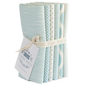 May include: A bundle of fabric squares in various patterns, including stripes, dots, and stars, in shades of light blue and white. The fabric is held together with a ribbon and a tag that reads "Classic Basics".