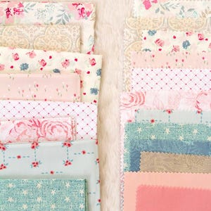 Puede incluir: Una colecci&oacute;n de muestras de tela plegadas en varios dise&ntilde;os florales y estampados. La paleta de colores incluye rosas, azules y cremas. Algunas telas presentan peque&ntilde;as estampados florales, mientras que otras tienen patrones de rosas m&aacute;s grandes. Las telas est&aacute;n dispuestas sobre una superficie blanca y esponjosa.