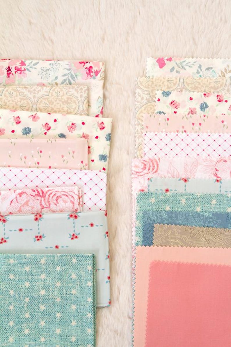 Puede incluir: Una colecci&oacute;n de muestras de tela plegadas en varios dise&ntilde;os florales y estampados. La paleta de colores incluye rosas, azules y cremas. Algunas telas presentan peque&ntilde;as estampados florales, mientras que otras tienen patrones de rosas m&aacute;s grandes. Las telas est&aacute;n dispuestas sobre una superficie blanca y esponjosa.