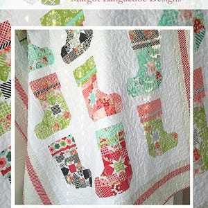 May include: A white quilt featuring appliqued Christmas stockings in various patterns and colors, including red, green, and black. The quilt has a quilted design and the text "Ready for Santa". The Pattern Basket logo is at the top.