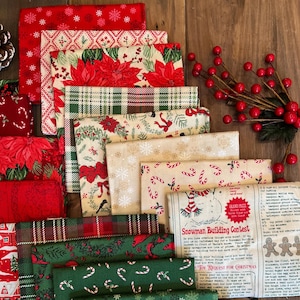 May include: A collection of folded fabric squares featuring Christmas patterns including red poinsettias, green plaid, candy canes, snowflakes, and a cream-colored panel with text titled Snowman Building Contest and a recipe for gingerbread.