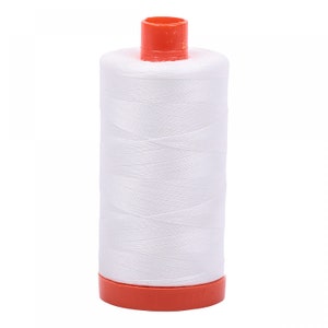 May include: A white spool of thread with an orange plastic top and bottom.