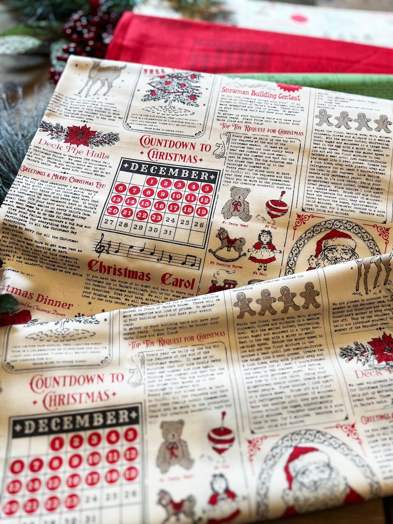 May include: A cream-colored fabric featuring a repeating Christmas-themed newspaper print in red and black ink. The design includes a December calendar, gingerbread men, a Santa Claus illustration, and various holiday-themed text sections.