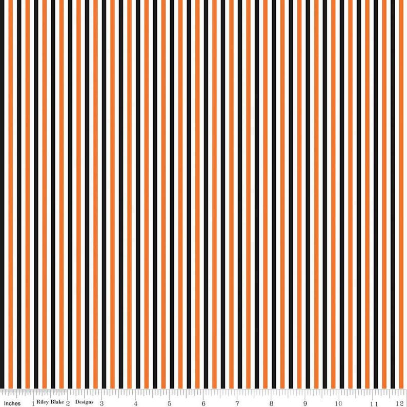 May include: Vertical striped fabric with alternating black, orange, and white stripes. The fabric is measured in inches, with the text "Riley Blake Designs" visible.