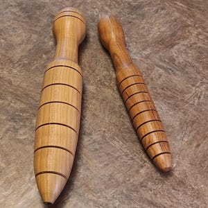 May include: Two wooden tools with a grooved design. The larger tool is about 10 inches long and the smaller tool is about 6 inches long.