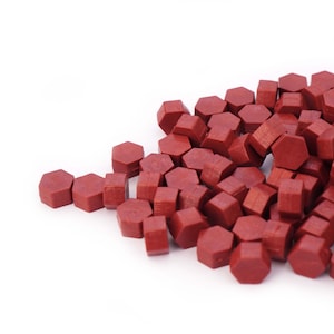 May include: A pile of red wax sealing pellets, hexagonal in shape, for sealing envelopes or letters.
