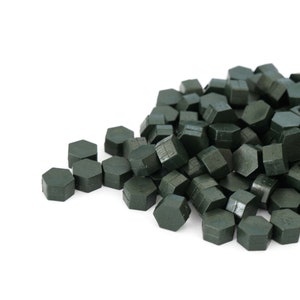 May include: A pile of dark green wax seal pellets, hexagonal in shape, for sealing envelopes or letters.