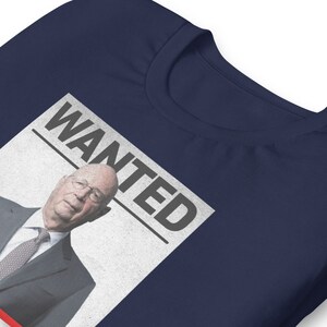 May include: A navy blue t-shirt with a white poster that says "WANTED" and features a photo of a man in a suit and tie.