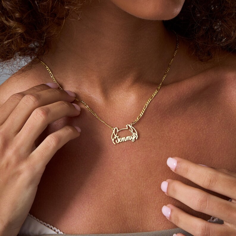 May include: A gold necklace with a delicate chain and a pendant featuring the name "Jenny" in a cursive script.