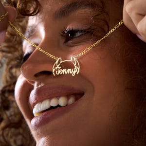 May include: A gold necklace with a delicate chain and a pendant featuring the name "Jenny" in a cursive script.