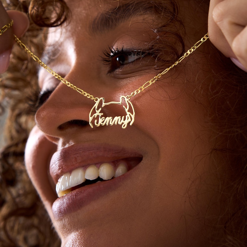 May include: A gold necklace with a delicate chain and a pendant featuring the name "Jenny" in a cursive script.
