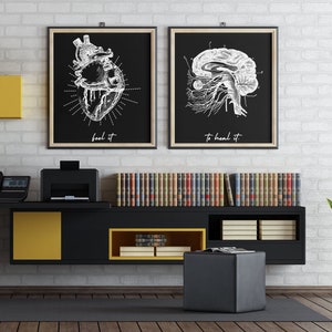 Könnte beinhalten: Schwarz-weiße anatomische Illustrationen eines Herzens und Gehirns mit dem Text "feel it" und "to heal it" an einer weißen Backsteinwand über einem schwarzen und gelben Regal mit Büchern und einer Pflanze.
