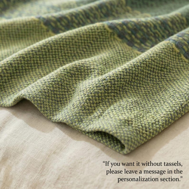 May include: Close-up of a textured, woven fabric in shades of green and gray. The fabric has a subtle pattern and a soft, inviting appearance. The text in the image reads: "If you want it without tassels, please leave a message in the personalization section."